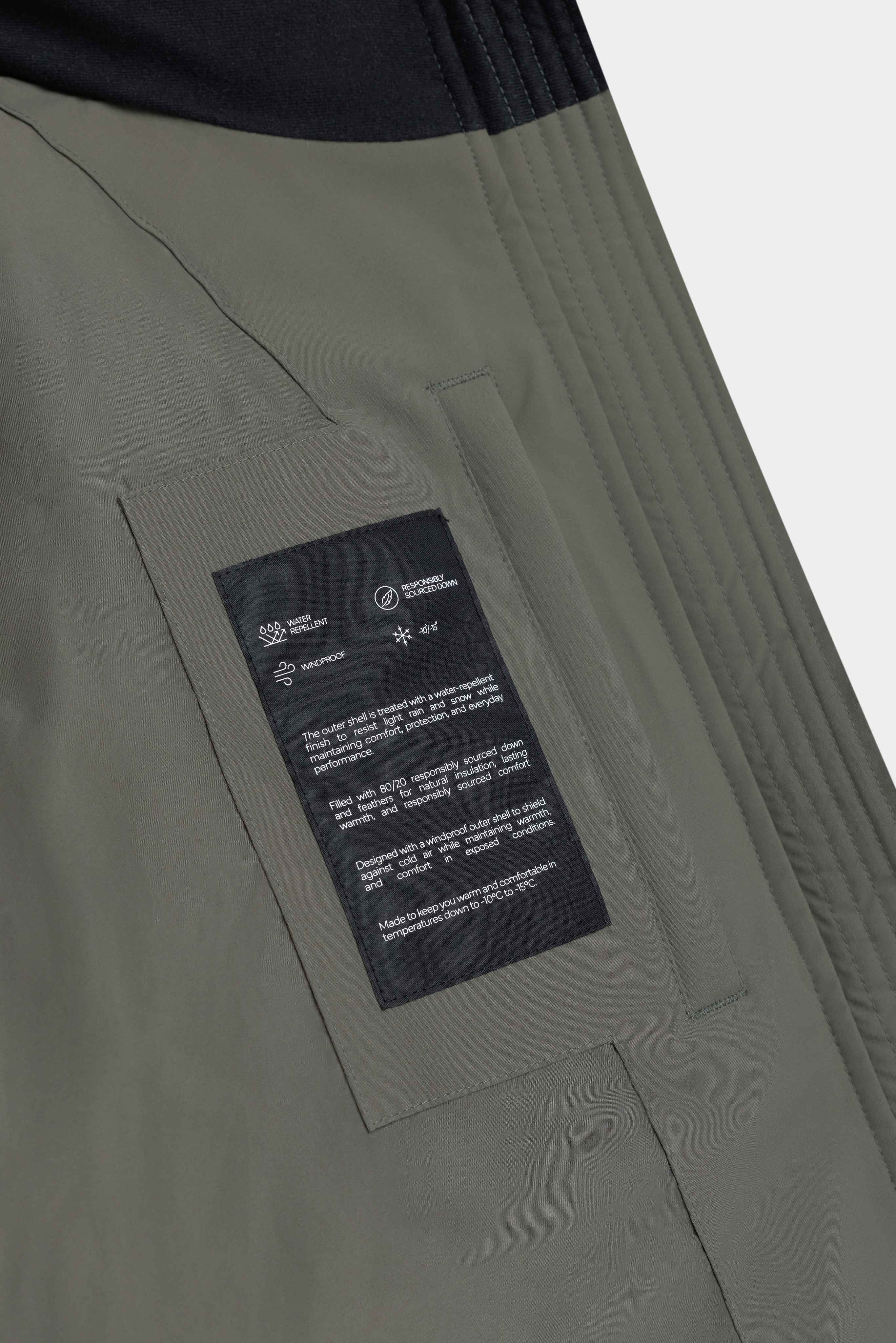 Inside pocket and technical specifications label on the khaki CASPARA Aurora puffer jacket.